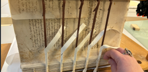 Archival book with no binding attached to a large wooden device for treatment.
