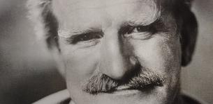 Black and white headshot of a middle aged man with a moustache.
