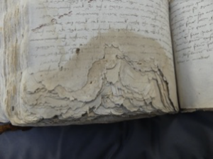 Open archival book with badly worn pages and visible deterioration. 