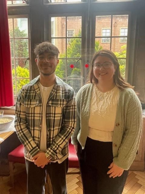 A man and woman standing next to each other in front of a large window.