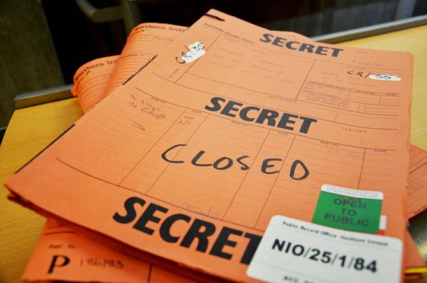 Stack of three orange files, the top one has writing on it reading "secret" and " Closed".