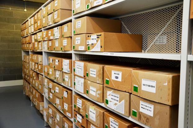 Bay of shelves stacked with archival boxes with labels on the front.