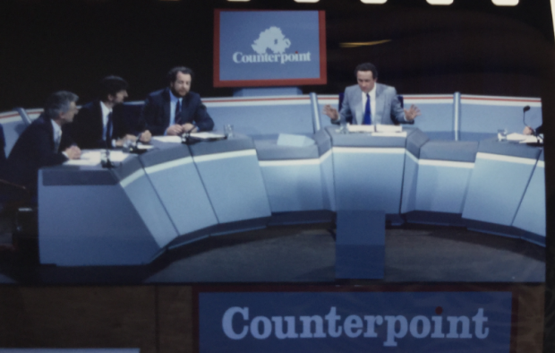 Coloured photograph of a large panel table with three men grouped together on the right side, one in the middle and the hand of another visible on the right side. The background features a screen with an outline of a map of Northern Ireland and the word 'Counterpoint'.