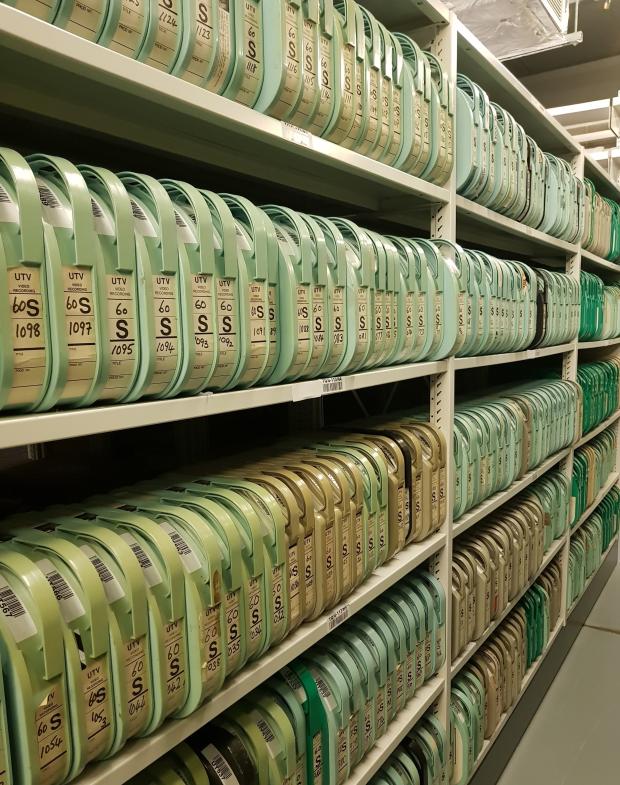 Image of multiple rows of shelves containing green one-inch tape containers.