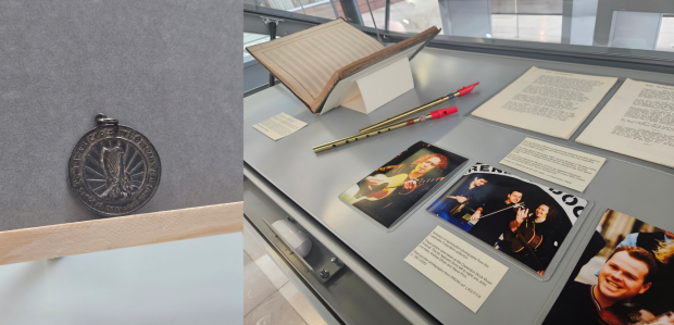 Two images side-by-side. The image on the left shows a dark silver medal with a harp design on display. The image on the right shows documents and artefacts on display in the case including two tin whistles, photographs of men playing instruments, typescript diary entries and a music manuscript book.