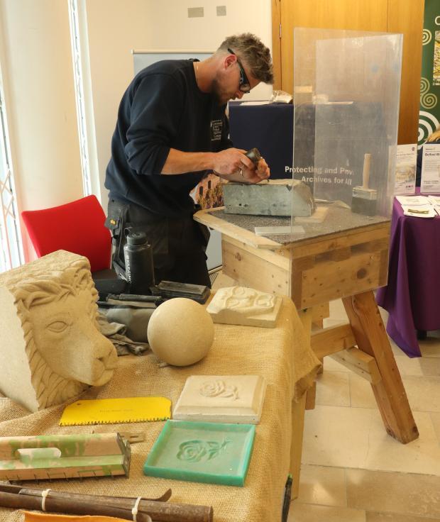 A man wearing goggles working on sanding a window frame